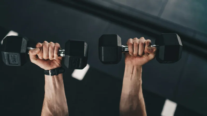 Femme choisissant l’haltère suivant sur un rack dans une salle de sport