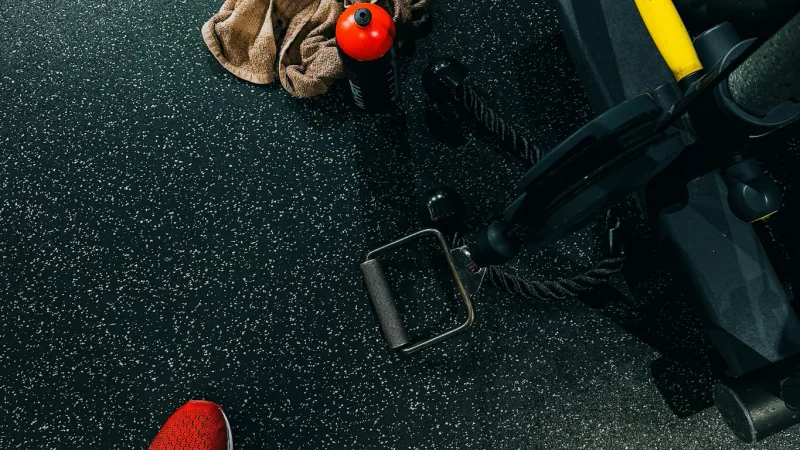 Barre vide posée sur un rack, avec la salle de sport en arrière-plan