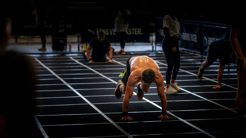 Athletes doing burpees on a marked training floor.