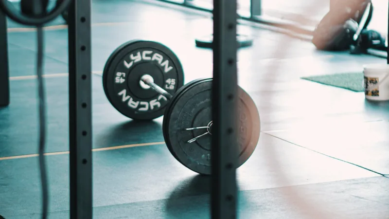Beladene Langhantel auf dem Boden neben einem Squat Rack.