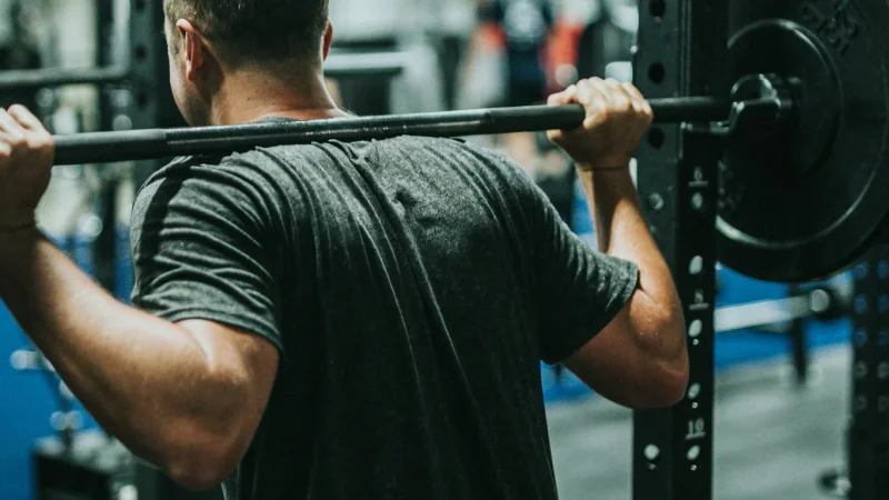 Femme en goblet squat profond avec kettlebell, vue de profil dans une salle ensoleillée
