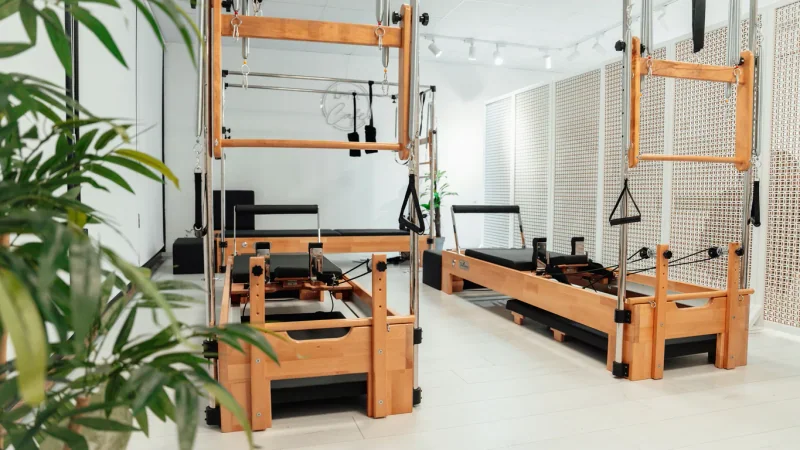 Studio de Pilates lumineux avec reformers en bois, ressorts et plantes