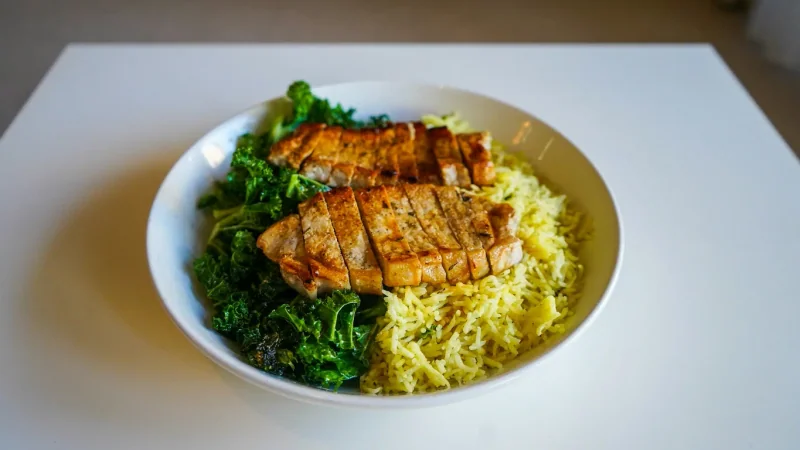 Plate of grilled chicken, rice and green vegetables.