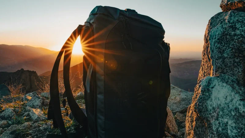 Sac à dos entre des rochers, éclairé par un soleil bas.