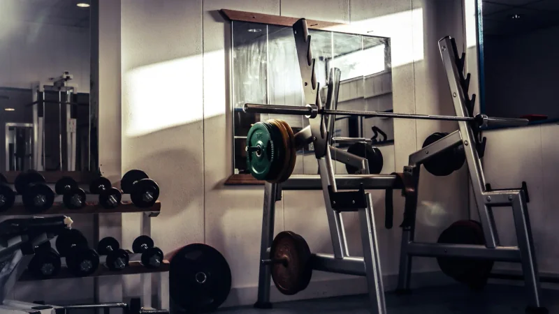 Vue sur une barre et plusieurs appareils dans une salle de musculation