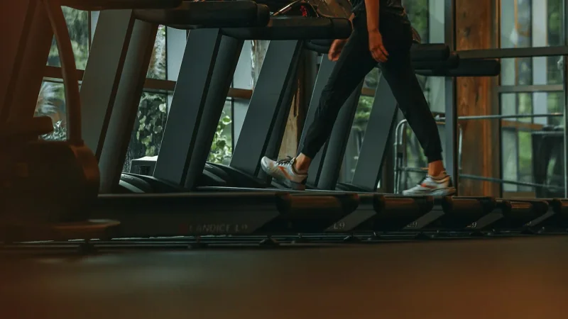 Person on a treadmill beside other treadmills in a gym.